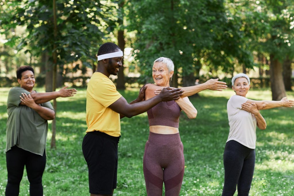 Trainer Assisting a Woman with Stretching Exercises in a Park.