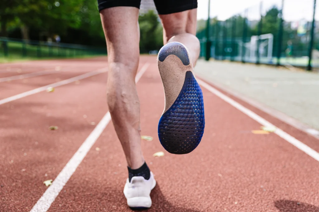 Sprinter fit man on running tracks at outdoor stadium - Why Elite Sports Podiatry is the Future of Foot and Movement Health - Foot Suite
