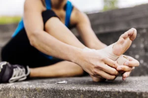 Woman wrapping foot in bandage - Why Active People Experience Foot Pain After Workouts - Foot Suite